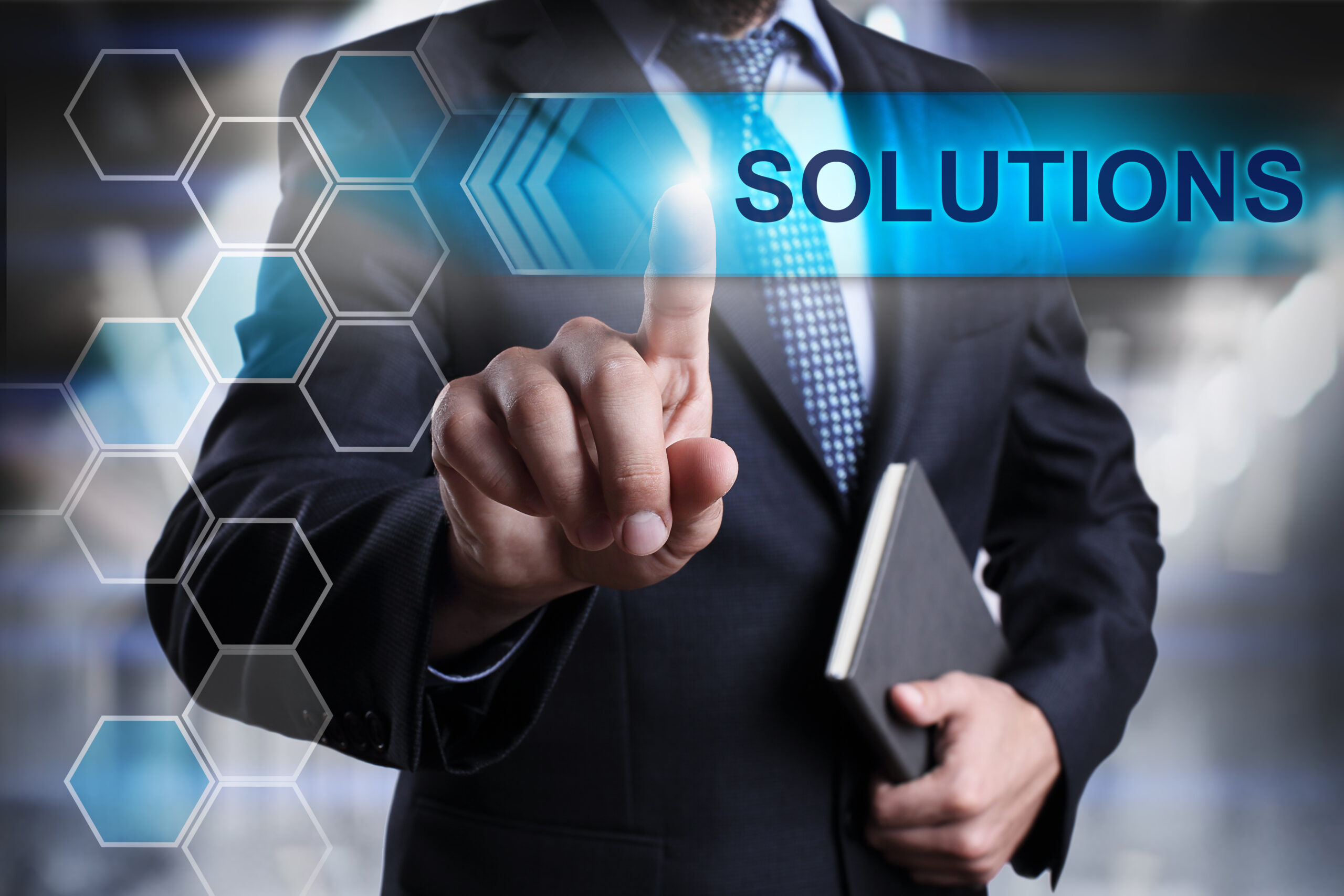 Businessman in a suit interacts with a digital interface displaying the word "Solutions," symbolizing innovation and problem-solving.